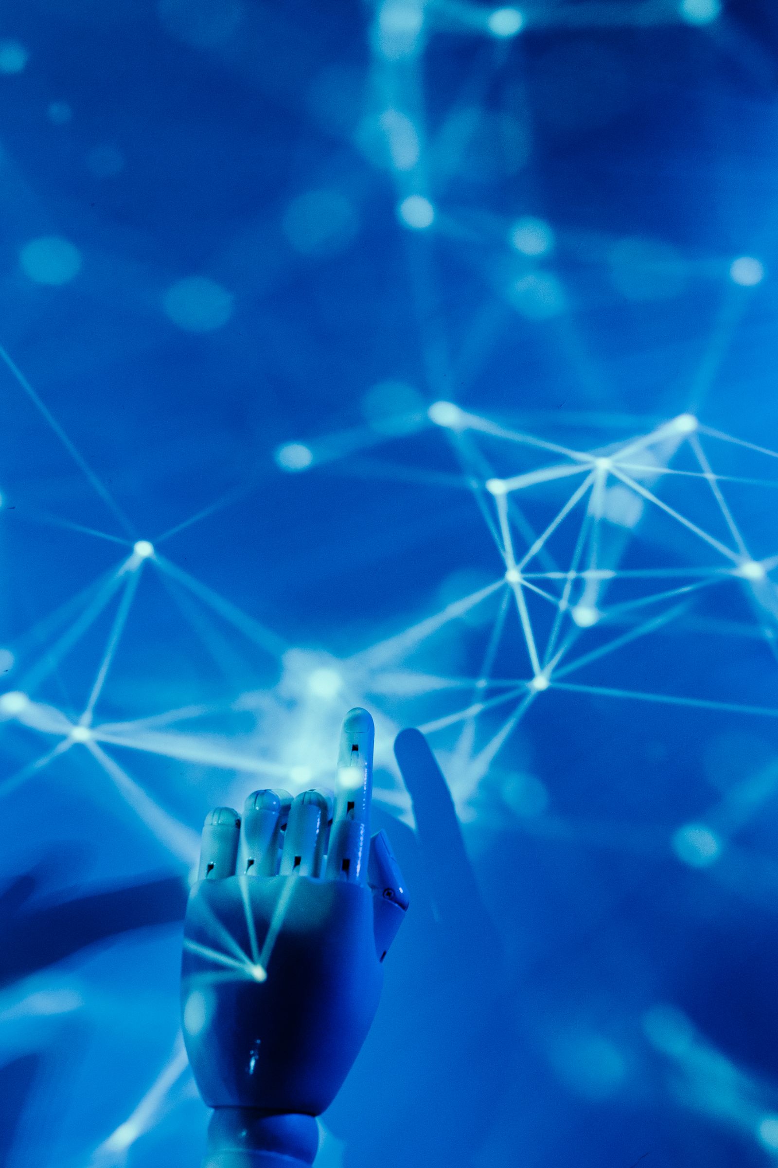 Main robotique touchant un réseau digital sur fond bleu — intelligence artificielle en entreprise