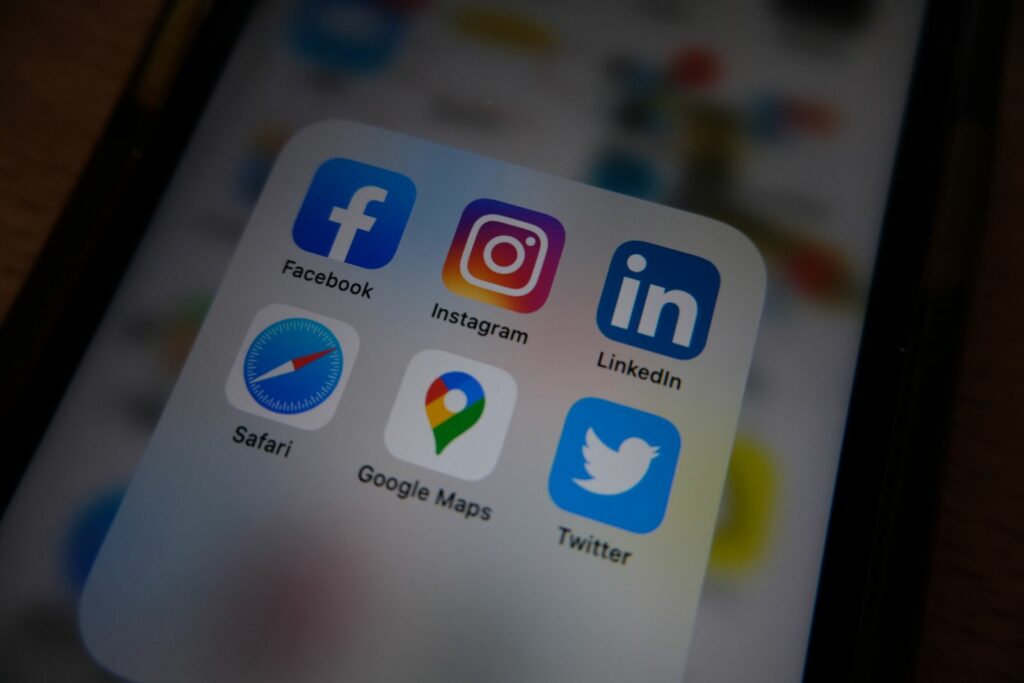 Smartphone affichant les icônes des réseaux sociaux (Facebook, Instagram, LinkedIn)